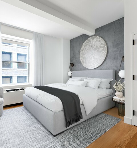 Three Bedroom Apartments in Financial District, NY - 63 Wall Street - Bedroom with Wood-Style Flooring, Area Rug, Large Bed, Nightstands, Plush Armchair, White Dresser, and Large Window.